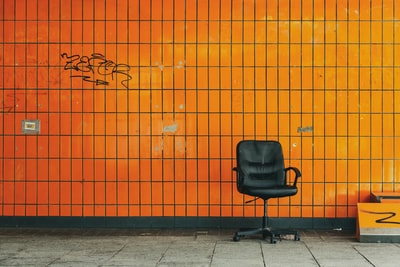 Orange walls rolling black leather chair
